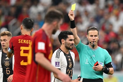 Dutch referee Danny Makkelie presents a yellow cart to Spain's midfielder #05 Sergio Busquets for fouling Germany's midfielder #14 Jamal Musiala during the Qatar 2022 World Cup Group E football match between Spain and Germany at the Al-Bayt Stadium in Al Khor, north of Doha on November 27, 2022. (Photo by Glyn KIRK / AFP)