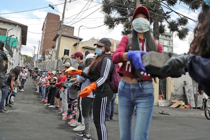 Las personas se pasan ladrillos que quedaron tirados en las calles luego de las protestas.