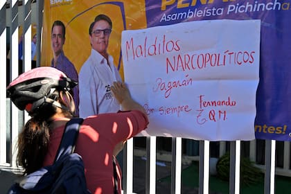 Una ciclista coloca un cartel en homenaje a Villavicencio y en repudio del crimen organizado y sus presuntos lazos con autoridades.