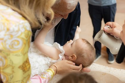 Eduardo sostiene la cabeza de
su hija mientras el padre Carlos
Checo vierte el agua bendita