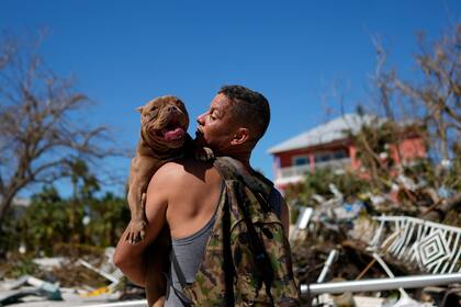 Eduardo Tocuya lleva un perro al que rescató con esperanzas de reunirlo con sus dueños, dos días después del paso del huracán Ian por Fort Myers, Florida