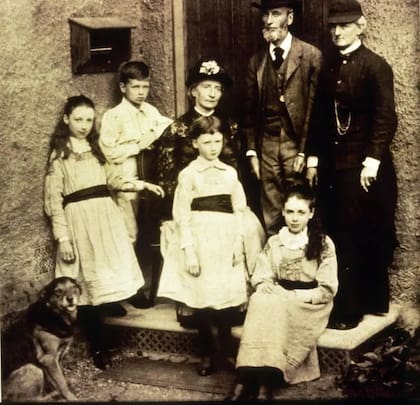 Eglantyne sentada en el escalón de la entrada de la casa con su tía y familiares, en 1882