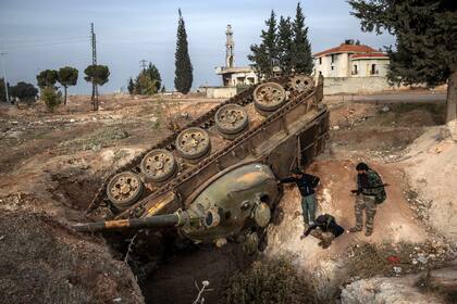 El 16 de diciembre de 2024, en las afueras de Homs (Siria), combatientes rebeldes comprueban un tanque volcado que quedó después de que soldados del régimen de Assad lucharan contra los rebeldes que avanzaban desde el norte.