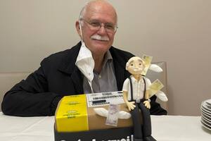 El abuelo posa sonriente con la torta de la compañía que tanto admira