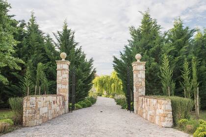 El acceso a la propiedad se realiza a través de un portón de hierro con muretes y columnas de piedra, en donde ya se vislumbra  el estilo de La Toscana.