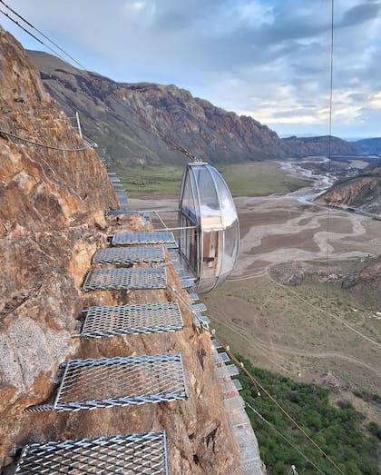 El acceso por la vía ferrata, una estructura segura que permite a los visitantes llegar a la cápsula sin riesgos, mientras disfrutan de una vista sin igual hacia los valles y montañas