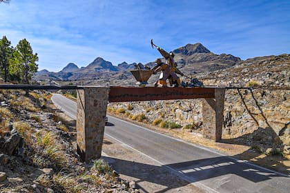 El acceso rutero al pueblo, con homenaje a los mineros extrayendo el oro