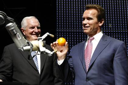 El actor de Terminator y ex-gobernador de California, Arnold Schwarzenegger, toma una naranja de la mano del robot Marvin junto a Craig Barrett, CEO de Intel, en la feria CeBit en 2009