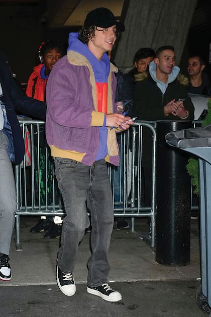 El actor de Wonka eligió un oufit más descontracturado de campera lila, buzo azul con capucha, jeans, zapatillas y gorrita.