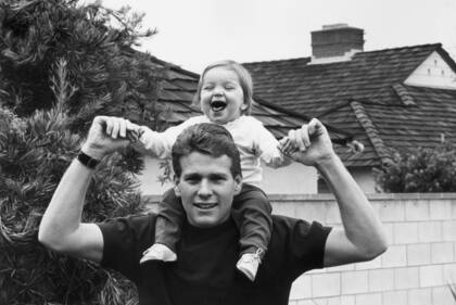 El actor Ryan O'Neal sosteniendo en brazos a una pequeña Tatum