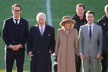 El actor Ryan Reynolds, el Rey Carlos, la Reina Consorte Camila y el actor Rob McElhenney, en el campo de juego de Wrexham, el club adquirido por las estrellas de Hollywood en febrero de 2021

