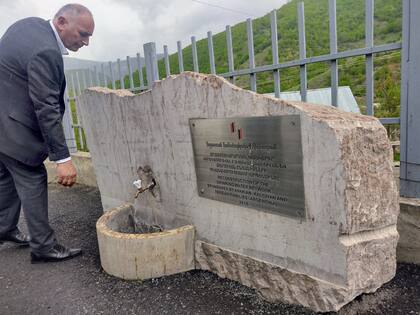 El alcalde de Khachardzan muestra el monolito que recuerda la inauguración de la red de agua corriente