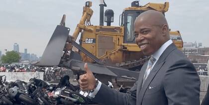 El alcalde de Nueva York posa feliz frente a la excavadora que destruyó un centenar de vehículos todoterreno que aterrorizaban a los habitantes de la ciudad