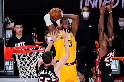 El alero de Los Angeles Lakers, LeBron James, pasa entre el escolta del Miami Heat, Duncan Robinson, a la izquierda, y el alero Jimmy Butler durante la segunda mitad del Juego 4 de las Finales de la NBA, el martes 6 de octubre de 2020, en Lake Buena Vista, Florida.