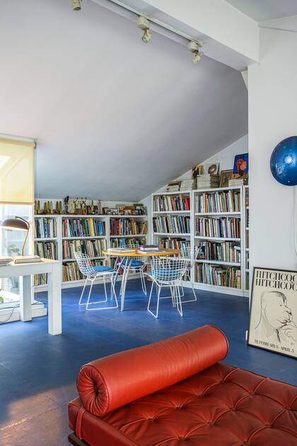 El altillo de techos inclinados hoy un estudio repleto de luz, libros, premios y hasta una pequeña terraza con cactus. Allí se destaca una chaise longue de Le Corbusier tapizada de rojo (Manifesto) y un luego de sillas Bertoia vintage.