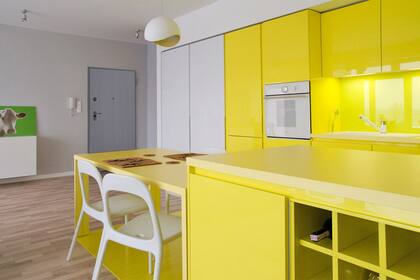 El amarillo shocking en esta cocina integrada permite delimitar áreas dentro del mismo entorno