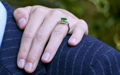 El anillo de compromiso lleva una esmeralda verde rodeada de pequeños diamantes