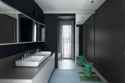 El antebaño incorpora un amplio placard que unifica funciones con el vestidor (Zona M). Banquito ‘Bit’ en plástico reciclado (Normann Copenhagen).