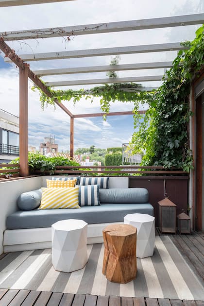 El área pública se abre a un balcón terraza con espacios de estar como este con sillón en chapa plegada hecho a medida, almohadones (Mercedes Segura), taburetes y alfombra rayada (Mihran).