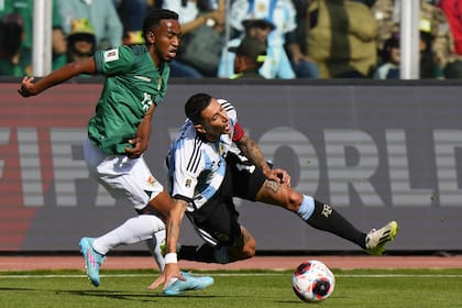 El argentino Ángel Di María cae desafiado por el boliviano Jaime Arrascaita durante un partido de fútbol de clasificación para la Copa Mundial de la FIFA 2026 en el estadio Hernando Siles de La Paz, Bolivia