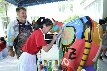 El artista argentino realizó una intervención artística sobre una vaca de acrílico de tamaño real junto a un grupo de niños de la escuela primaria 101 del distrito Dongcheng