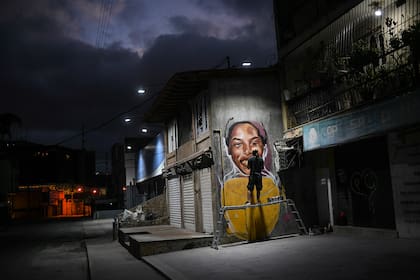El artista callejero Wolfgang Salazar trabaja en una mural de la atleta venezolana Yulimar Rojas en el barrio de Boleita, en Caracas 