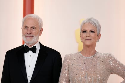 El artista Christopher Guest acompaña a su esposa Jamie Lee Curtis en la alfombra, que esta vez es de color champagne