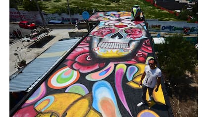 El artista mexicano Israel Zuniga en el techo de un edificio con su mural