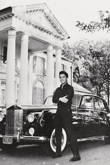 El astro posa con su Rolls-Royce frente a Graceland, su famosa mansión, circa 1960.