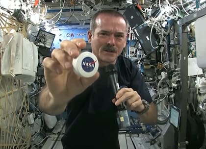 El astronauta canadiensa muestra la cápsula en la que guardan los trapos de limpieza