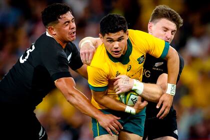 El australiano Noah Lolesio tackleado por los neozelandeses Anton Lienert-Brown y Beauden Barrett. Australia se tomó revancha tras la peor derrota en la historia del clásico.