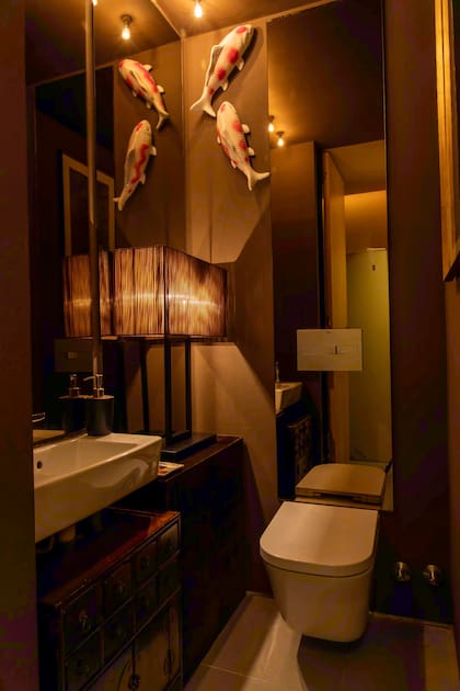 El baño aprovecha sus tonos oscuros y luces bajas para crear un ambiente de serenidad. Atención a los peces koi que nadan paredes arriba.