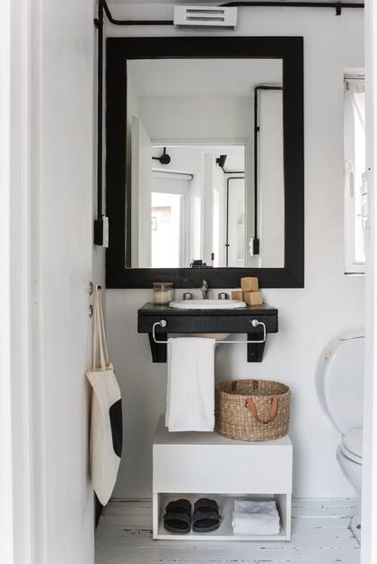 El baño, compacto, reitera el juego en blanco y negro. Toallas de The Linen Store.