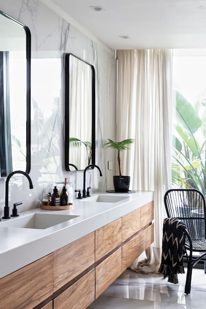 El baño, con muebles en petiribi y porcelanato símil calacatta, y espejos con marco en hierro negro