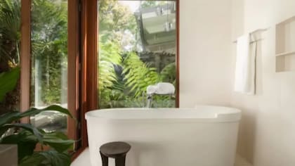 El baño cuenta con detalles modernos y grandes aberturas que ofrecen vistas directas al jardín