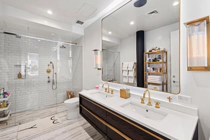 El baño cuenta con doble lavabo, un gigantesco espejo y doble ducha con mamparas transparentes