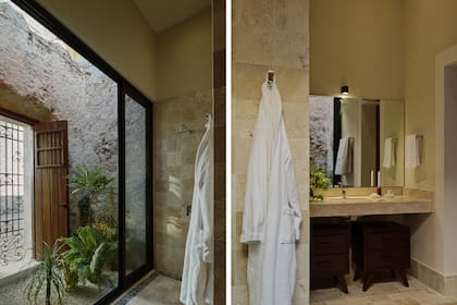 El baño en suite se separa del límite y abre sus vistas hacia un jardín interior con muros de piedra y puertas de madera, que aporta frescura y sensación de exterior.