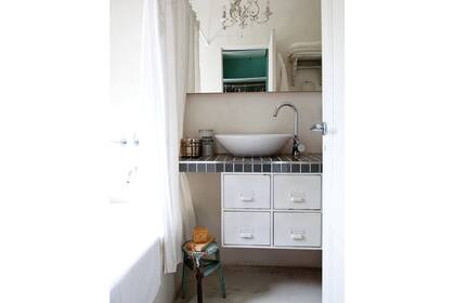 El baño en suite tiene una mesada de obra revestida con mosaicos y un mueble de guardado en chapa que fue un fichero de oficina (Mercado de pulgas)