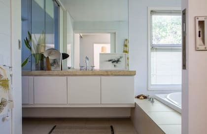 El baño mantiene el equipamiento de cuando se mudaron; paño (Plain Textiles) y obras (Lucila Sampayo) apoyadas sobre la mesada.