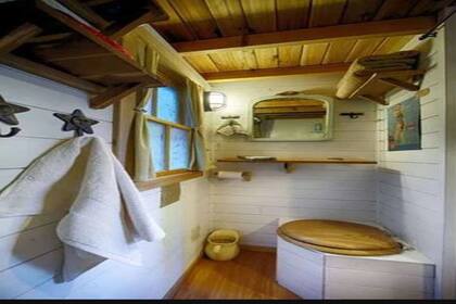 El baño mantiene una decoración simple y tiene una ducha y un inodoro. Los elementos que toman contraste son la madera y el color blanco.