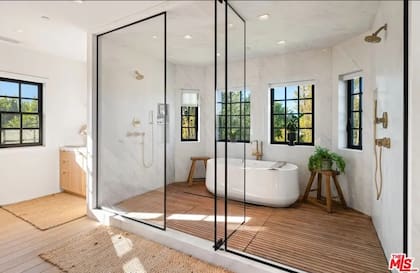 El baño principal, de estilo spa, está equipado con ducha con mampara de vidrio y acabados de alta gama