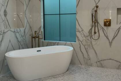 El baño principal se organiza con una bañera central y una pared cubierta por espejos