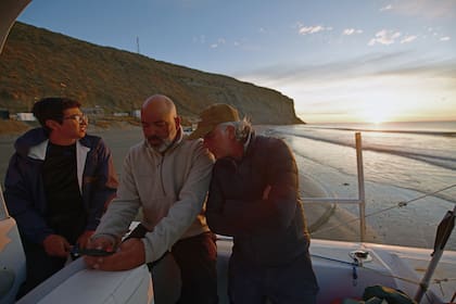 El biólogo Mariano Coscarella (izq) y el documentalista Juan Raggio (der) siguen en el celular las primeras señales de los rastreadores colocados a ballenas sei