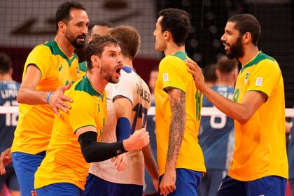 El brasileño Bruno Mossa Rezende levanta el puño mientras sus compañeros celebran un punto durante un partido del grupo B de la ronda preliminar de voleibol masculino contra Argentina, en los Juegos Olímpicos de Verano de 2020, el lunes 26 de julio de 2021, en Tokio, Japón. (Foto AP / Frank Augstein)