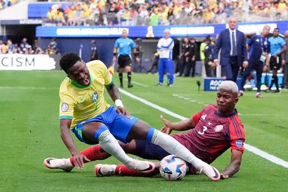 El brasileño Vinicius Júnior (izquierda) tras la barrida del costarricense Jeyland Mitchell en el partido por el Grupo D de la Copa América