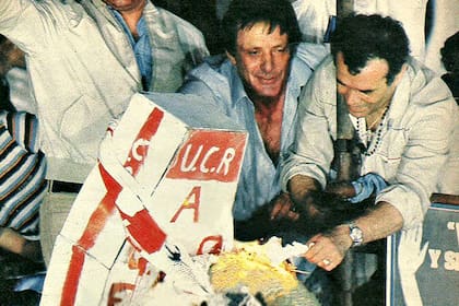 El cajón que incendió Iglesias tenía pintado a mano "UCR. Alfonsín. QEPD” con los colores del radicalismo: rojo y blanco. Junto al ataúd había una corona mortuoria y una botella de Coca-Cola. Herminio decía que Alfonsín era "el candidato de la Coca-Cola".