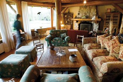 El cálido living de una de las casas repartidas en la propiedad, con grandes ventanales y vistas al lago.