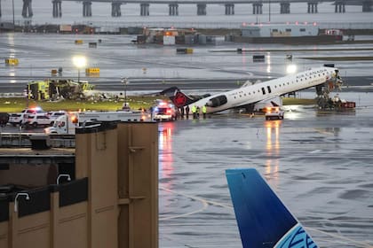 El camión de bomberos colisionado por el jet de Air Canada Express se observa tumbado en el extremo superior izquierdo de la imagen