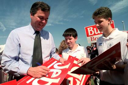 El candidato a gobernador republicano de Florida, Jeb Bush, a la izquierda, firma autógrafos en carteles de campaña para estudiantes en la Academia Brandon durante un mitín en 1998 en Tampa