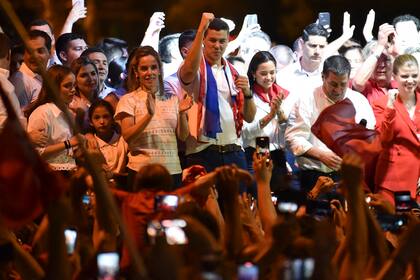 El candidato presidencial paraguayo por el Partido Colorado, Santiago Peña, celebra junto a su esposa, Leticia Ocampos de Pea, y el expresidente paraguayo Horacio Cartes, tras ganar las elecciones presidenciales en Asunción el 30 de abril de 2023.